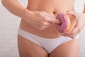 A faceless woman in white panties holds a pink donut imitating sex. A hint of a gesture of sexual intercourse