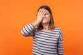 Facepalm. Portrait of forgetful upset woman with brown hair in long sleeve shirt. indoor studio shot isolated on orange background