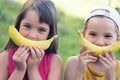 Faces of a beautiful young girl and boy with banana smile on nature background.