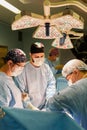 The faces of doctors surgeons in masks are a big plan, an operating room, a surgeon performs an operation in a modern Royalty Free Stock Photo