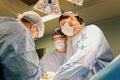 The faces of doctors surgeons in masks are a big plan, an operating room, a surgeon performs an operation in a modern Royalty Free Stock Photo