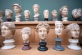 Faces and marble heads copies of old Roman gods and emperors on shelf. Memories about human of ancient world