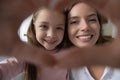 Faces of mom and daughter join fingers showing love symbol