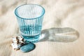 Faceted blue glass on white sand next to seashell, seashore. Drink clean water.