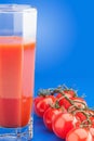 Faceted glass of tomato juice and branch of cherry tomatoes Royalty Free Stock Photo