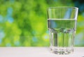 Faceted glass of water on nature background. Royalty Free Stock Photo