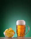 Faceted mug of light beer with foam and chips Royalty Free Stock Photo