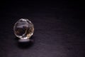 Faceted sphere, sparkling crystal on dark, black background. Large glass with light refraction, stone backdrop. Empty space for Royalty Free Stock Photo