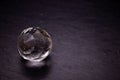 Faceted sphere, sparkling crystal on dark, black background. Large glass with light refraction, stone backdrop. Empty space for Royalty Free Stock Photo