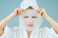 Facial care and beauty treatments. Beautiful woman with a sheet moisturizing mask on her face Royalty Free Stock Photo