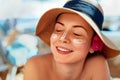 Facial Care. Female Applying Sun Cream and Smiling. Beauty Face. Portrait Of Young Woman in hat Smear Moisturizing Royalty Free Stock Photo