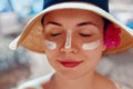 Facial Care. Female Applying Sun Cream and Smiling. Beauty Face.  Portrait Of Young Woman Smear  Moisturizing Lotion on Skin. Royalty Free Stock Photo