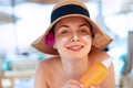 Facial Care. Young  Female Holding Bottle Sun Cream and  Applying on Face Smiling. Beauty Face.  Portrait Of Young Woman in hat Sm Royalty Free Stock Photo