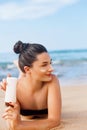 Facial Care. Young  Female Holding Bottle Sun Cream and  Applying on Face Smiling. Beauty Face.  Portrait Of Young Woman in hat Sm Royalty Free Stock Photo