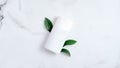 Facial cleanser shampoo bath bottle container branding mockup with green leaves on marble background. Flat lay, top view. Natural