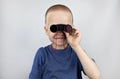 A boy with binoculars looks into the distance and smiles. Facial expression and body position show victory. The concept of vision