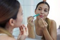 Facial hair removal. Close-up of beautiful young woman shaving her face by razor at home. Pretty girl using razor on bathroom Royalty Free Stock Photo