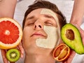 Facial mask from fresh fruits for man . Beautician apply slices.