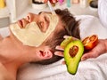 Facial mask from fresh fruits for man . Beautician apply slices.