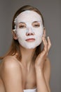 Facial mask. Woman using sheet mask on face skin for spa care Royalty Free Stock Photo