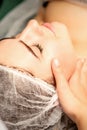 Facial massage. Hands of a masseur massaging neck of a young caucasian woman in a spa salon, the concept of health Royalty Free Stock Photo