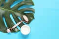 Massage roller and face cream on a monstera leaf, blue background, top view. Flat lay Royalty Free Stock Photo