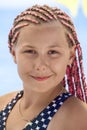 Facial portrait of young girl with long hair with dreds tressed pink fibre, outdoors, looking at camera