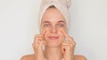 Facial rejuvenation. Healthy skin. Wellness regimen. Young woman with under-eye patches on her face wrapped in bath towel