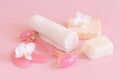 Facial roller, gua sha massager, towel and handmade soap bars near white orchid flower on pink