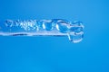 Facial serum with bubbles in transparent glass pipette and falling drop on blue background. Liquid gel or serum macro Royalty Free Stock Photo