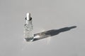 Facial serum with vitamin C in transparent glass bottle with pipette on grey background with trendy hard shadow. Natural Royalty Free Stock Photo