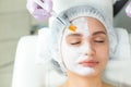 Facial skin care and protection. A young woman at a beauticians appointment. The specialist applies a cream mask to the