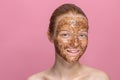 Facial skin scrub Coffee grounds mask on the face of a beautiful young woman Organic natural cosmetology Pink studio