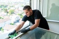 Facility management cleaner cleaning a window and window frame with green micro fiber cloths