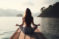 Facing back young woman practicing meditation or yoga, sitting on a wooden pier on the shore of a Royalty Free Stock Photo