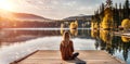 Facing back young woman , sitting on wooden pier on shore beautiful mountain lake at sunrise or Royalty Free Stock Photo
