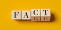 Fact and fake written on wooden blocks half flipped on yellow background, false and true, propaganda or news information concept Royalty Free Stock Photo