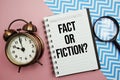 Fact Or Fiction? text written on notepad with alarm clock and magnifying glass Royalty Free Stock Photo