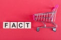 FACT word written on wood blocks with shopping trolley on background Royalty Free Stock Photo