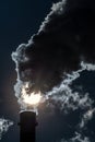 Factory chimney and coming out dark smokes in the sky and sun at background Royalty Free Stock Photo