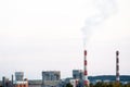 Factory chimneys against the gray autumn sky. Utopian landscape background. White toxic smoke is coming from a huge pipe.