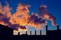 Factory chimneys smoke toxic substances above industrial building silhouette over beautiful sunset Royalty Free Stock Photo