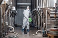 Factory cleaning. Man in protective suit and mask disinfects plant Royalty Free Stock Photo