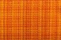 Factory fabric with yellow and red threads interspersed. Close-up long and wide texture of natural red fabric.