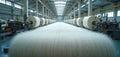 Factory interior showing a production line with large spools of fine white thread. Industrial machinery processes raw material Royalty Free Stock Photo