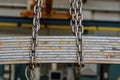 Factory overhead crane lifts iron strips on chains Royalty Free Stock Photo