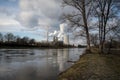 The factory smokes into the air on the shore of a beautiful river