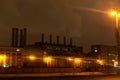 Factory with smoking pipes at night, with yellow lanterns