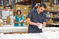 Factory Worker Checking Goods On Production Line