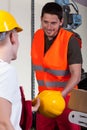 Factory worker giving his collaborator hardhat Royalty Free Stock Photo